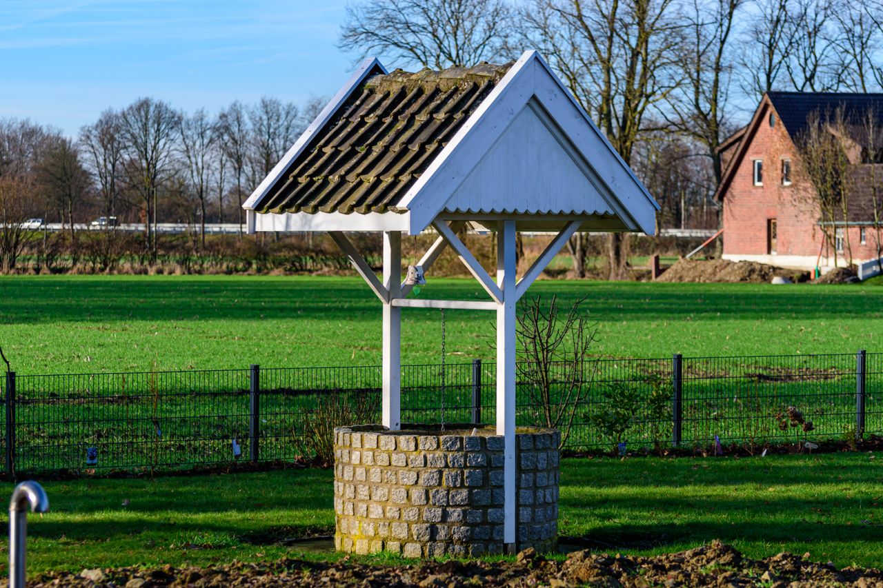 Classic stone well with wooden roof in Coesfeld's tranquil rural landscape.